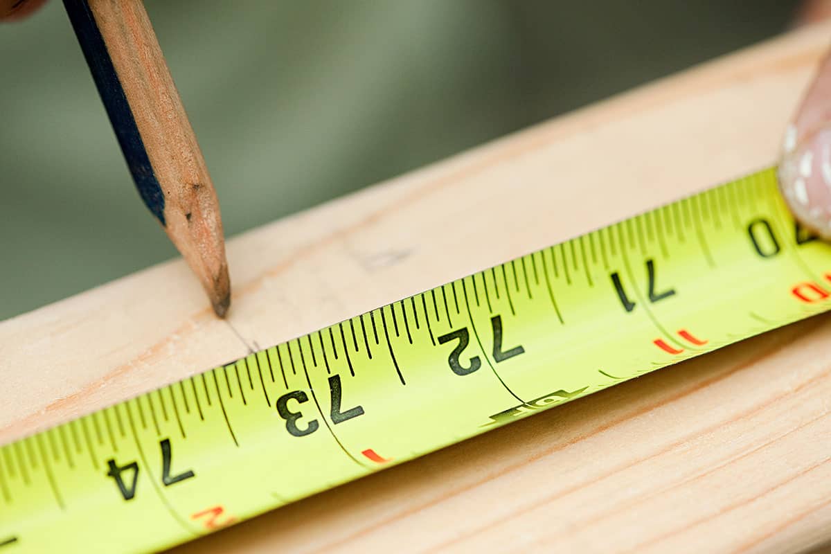 Measuring a plank of wood and marking with a pencil